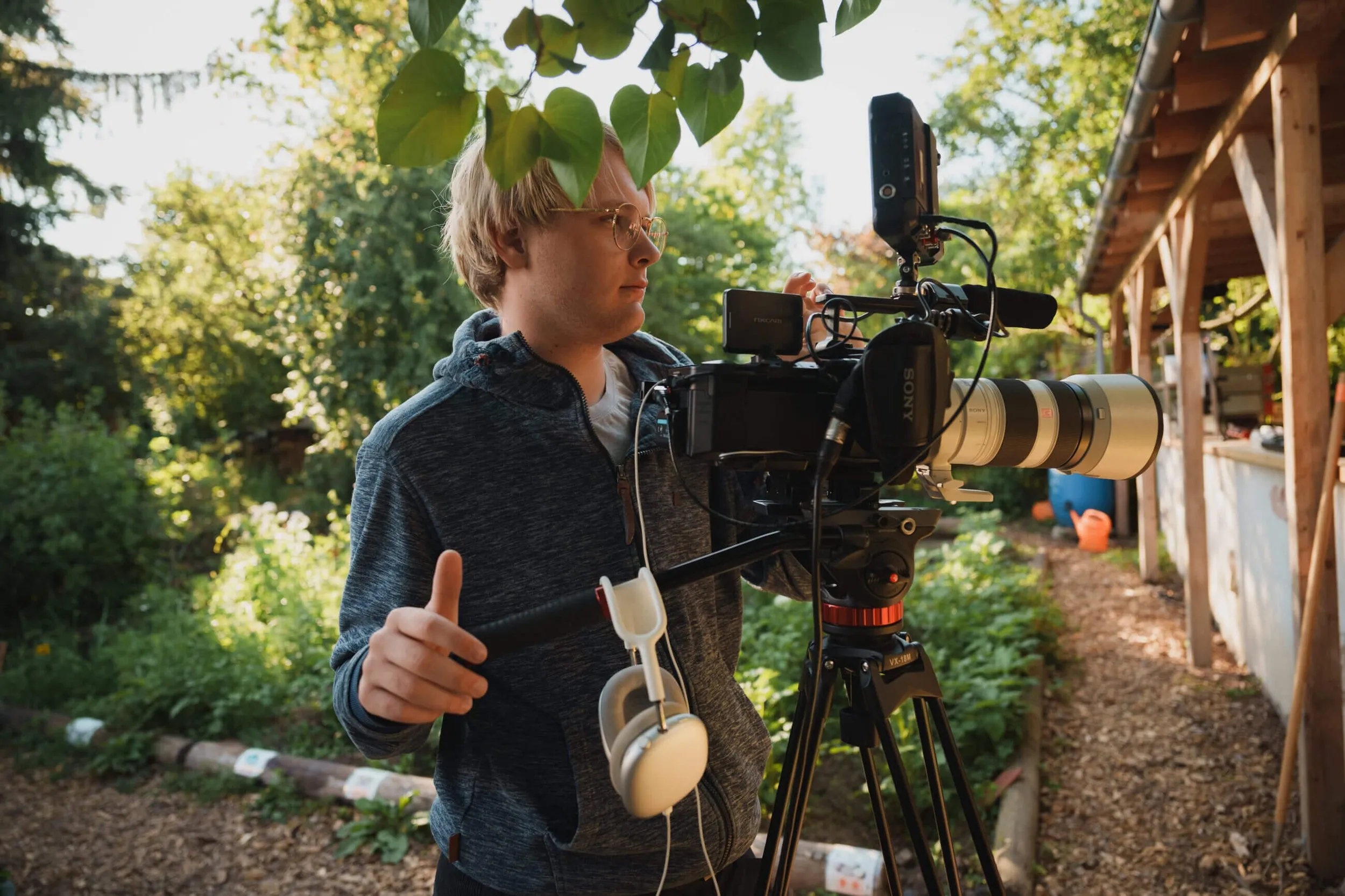 Camera operator setting up the camera on a tripod during an outdoor shoot